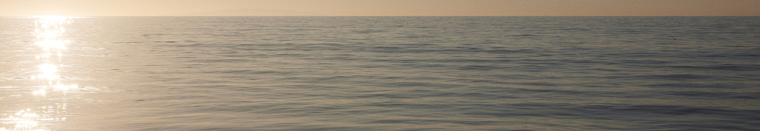 Calm ocean at sunset with a warm glow on the horizon
