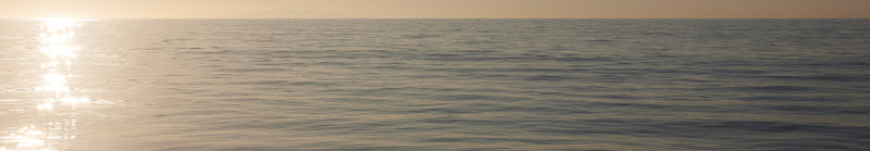 Calm ocean at sunset with a warm glow on the horizon